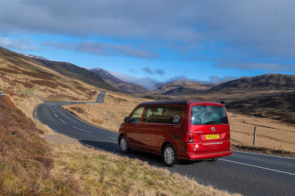 Campervan road trip with Four Seasons Campers in red VW California Campervan driving through Scottish Highlands