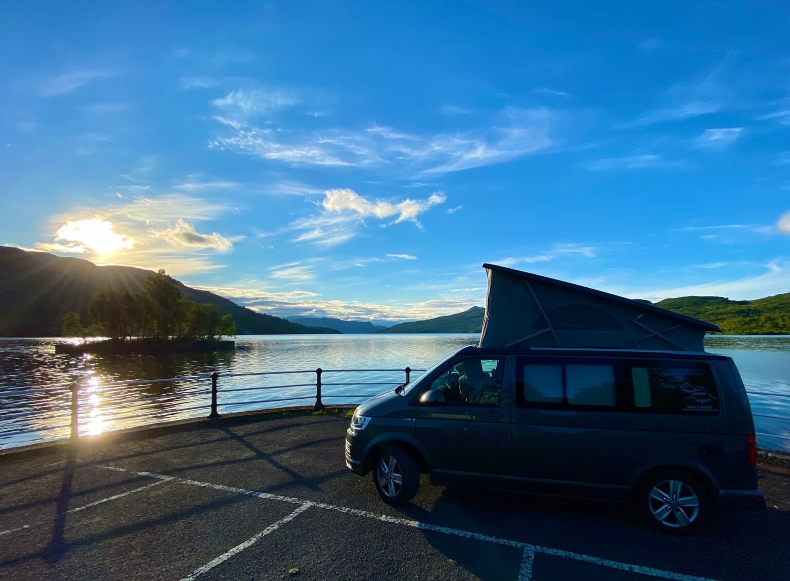 Campervan on Tour with Four Seasons Campers on the shore of Loch Katrine with bright blue sky