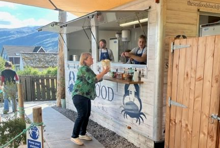 a lady at the Seafood Shack in Ullapool being served while on holiday with Four Seasons Campers