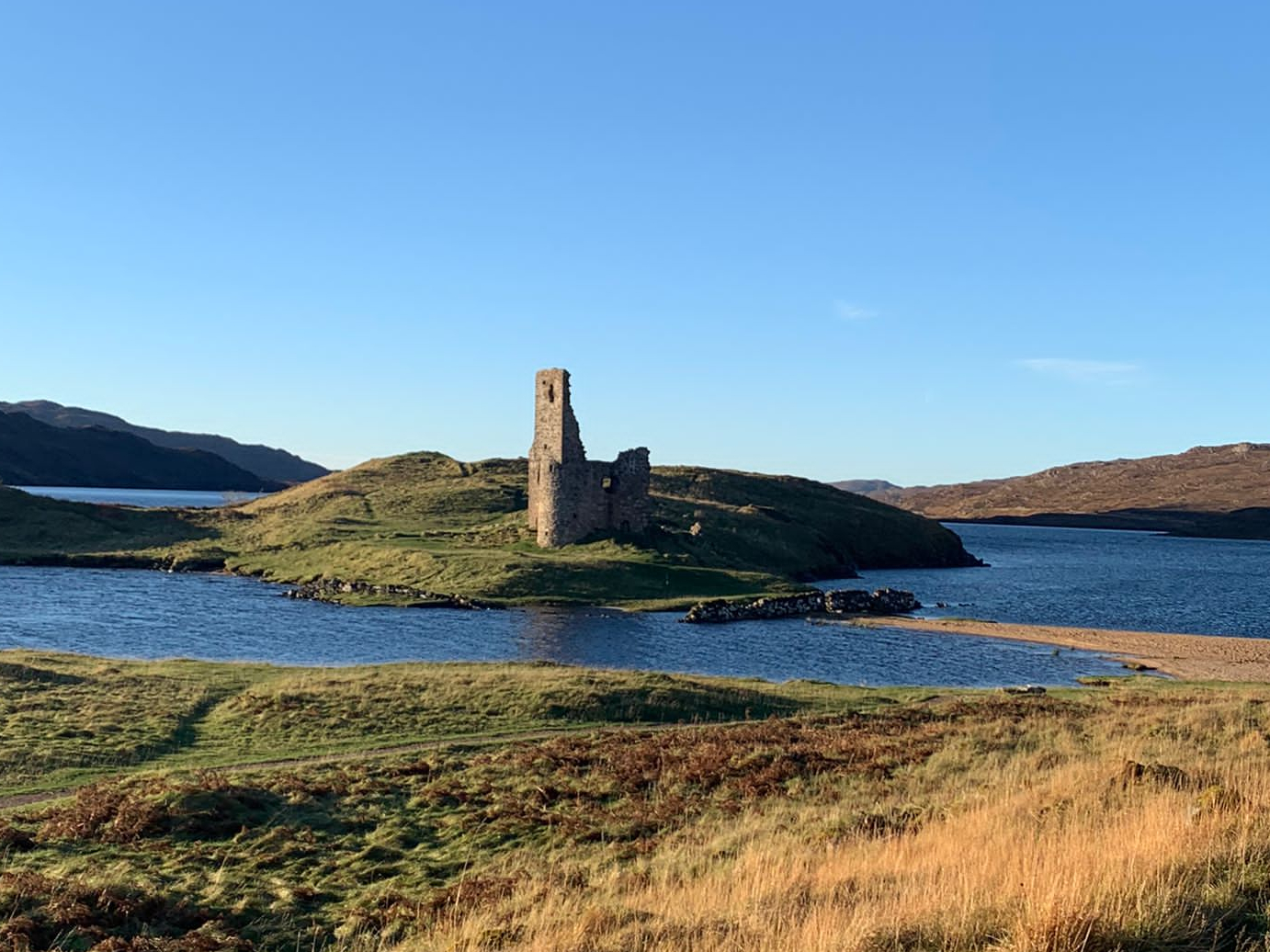 Ardvreck Castle on the shore fo Loch Assynt with blue skye taken on a RV Road trip with Four Seasons Campers