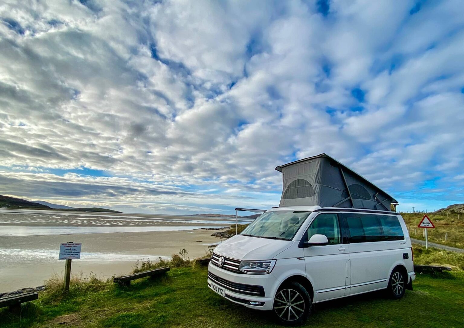 White Campervan with the roof up on the shore