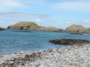 Beach at Iona Mull looking out onto Atlantic Ocean with islands and stone beach