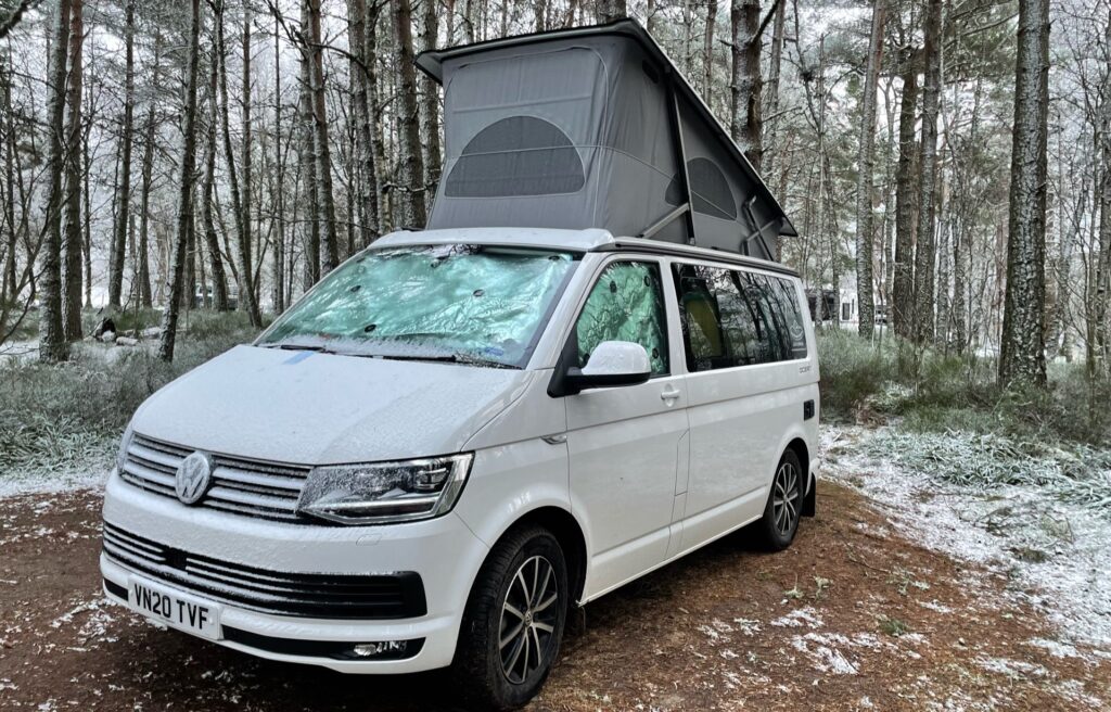 seasonal availability white campervan in woods with snow