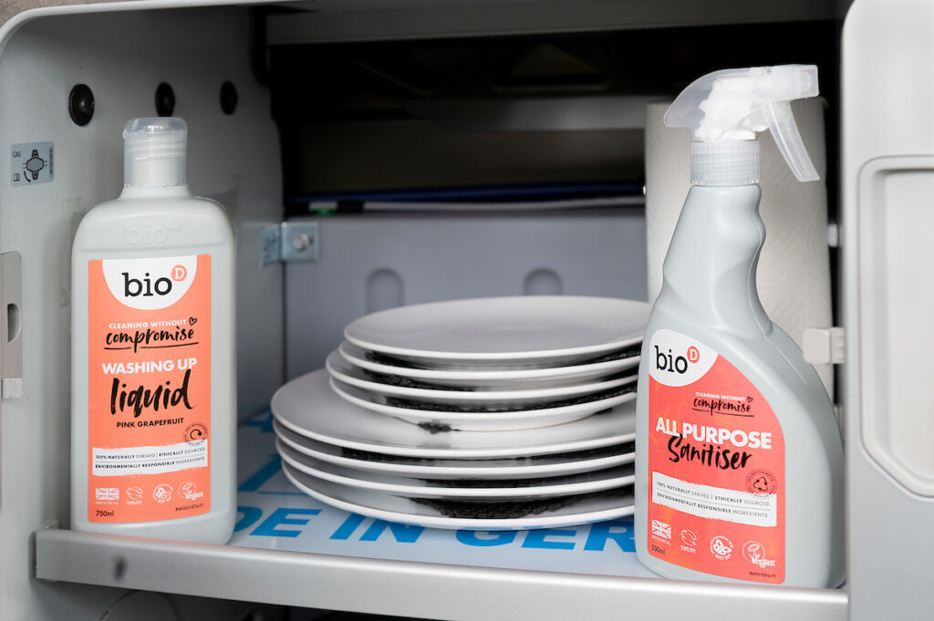 plates and eco cleaning products in campervan cupboard when hire campervan Four Seasons Campers