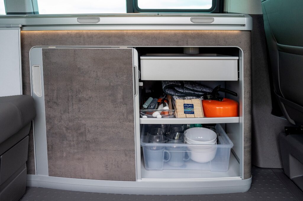 equipment for campervan hire in cupboard with cutlery drawer in campervan kitchen