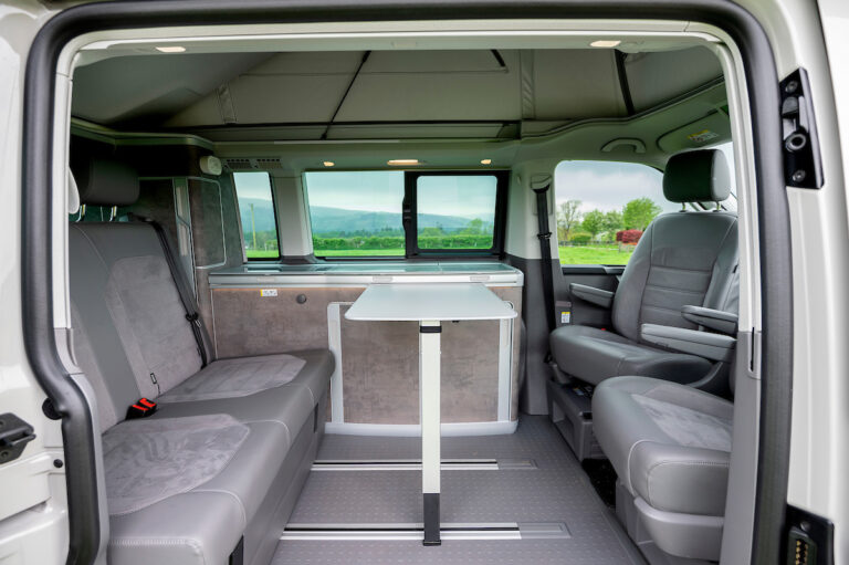 VW California Ocean campervan interior with leather look seats and table up and two front seats swivelled round to face rear