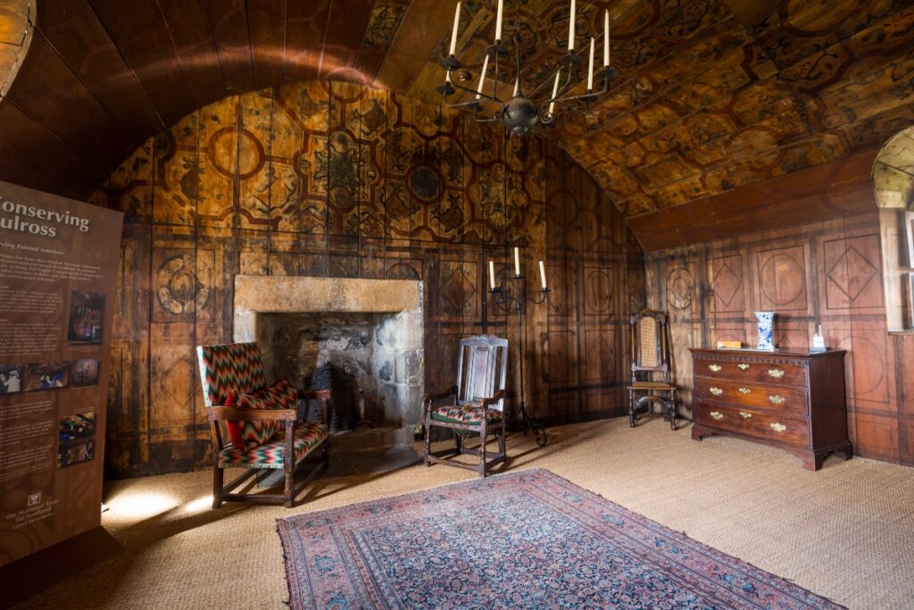 Interior of Culross palace showing arm chairs and fireplace and vaulted ceiling in Scotland