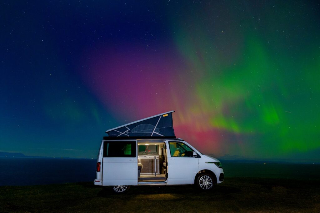 white four seasons campers campervan with pop up roof and red and green aurora at Gairloch in Scotland