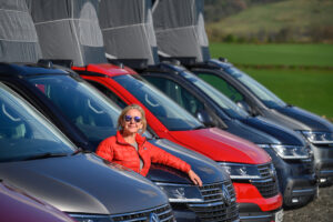 campervan fleet with pop up roofs at Four Seasons Campers with owner Liz in red jacket