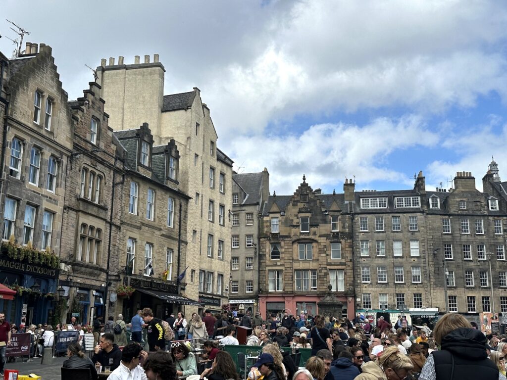 Grassmarket Edinburgh with old houses and people at tables drinking and eating