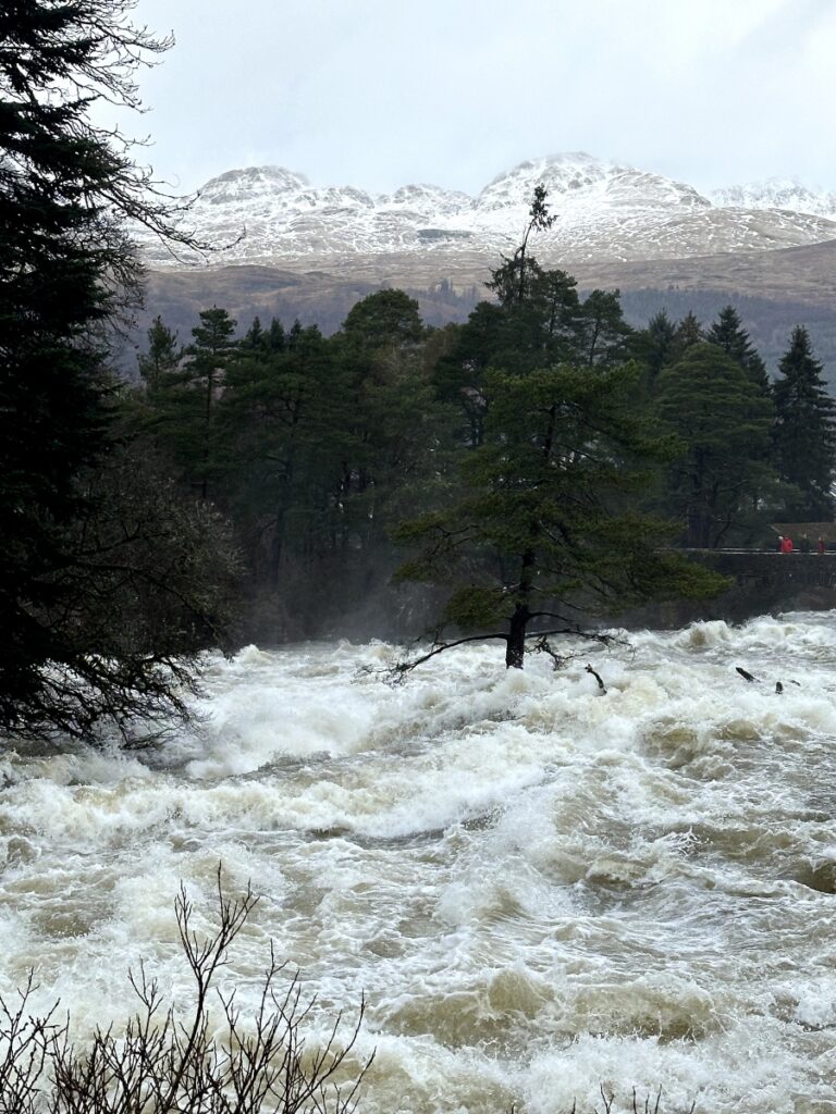 Falls of Killin Perthshire with snow hills in back ground and fur tree on left