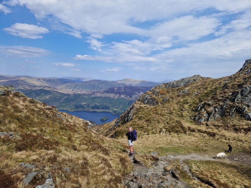 Girl hill walking up Ben Venue in Loch Lomond Scotland with 2 dogs on campervan road trip