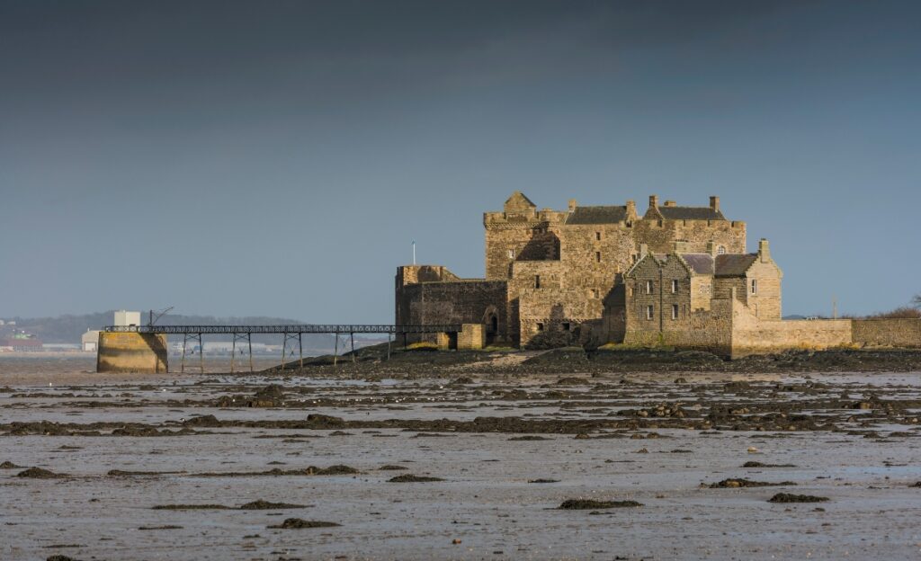 Blackness Castle beside sea and beach in the dusk with castle lit up near Edinburgh